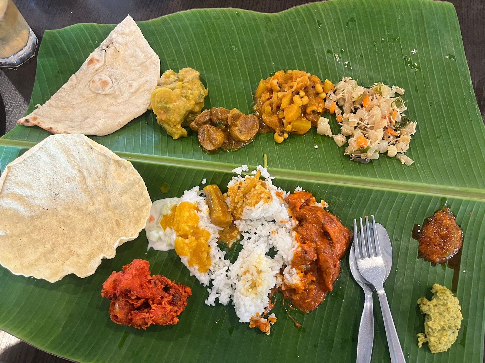 Two banana-leaf settings with rice, papadum, tandoori chicken, dhal and assorted vegetable curries