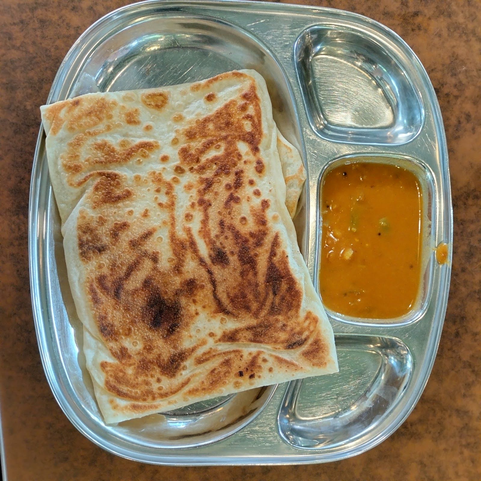 Folded griddled roti with a side of dhal in a steel tray